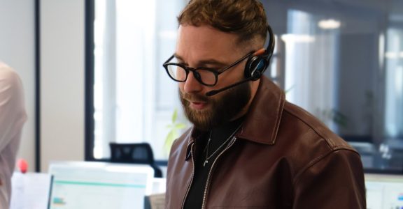 Conseiller du Cabinet Boman, casque sur les oreilles, renseignant un assuré sur ses garanties optique